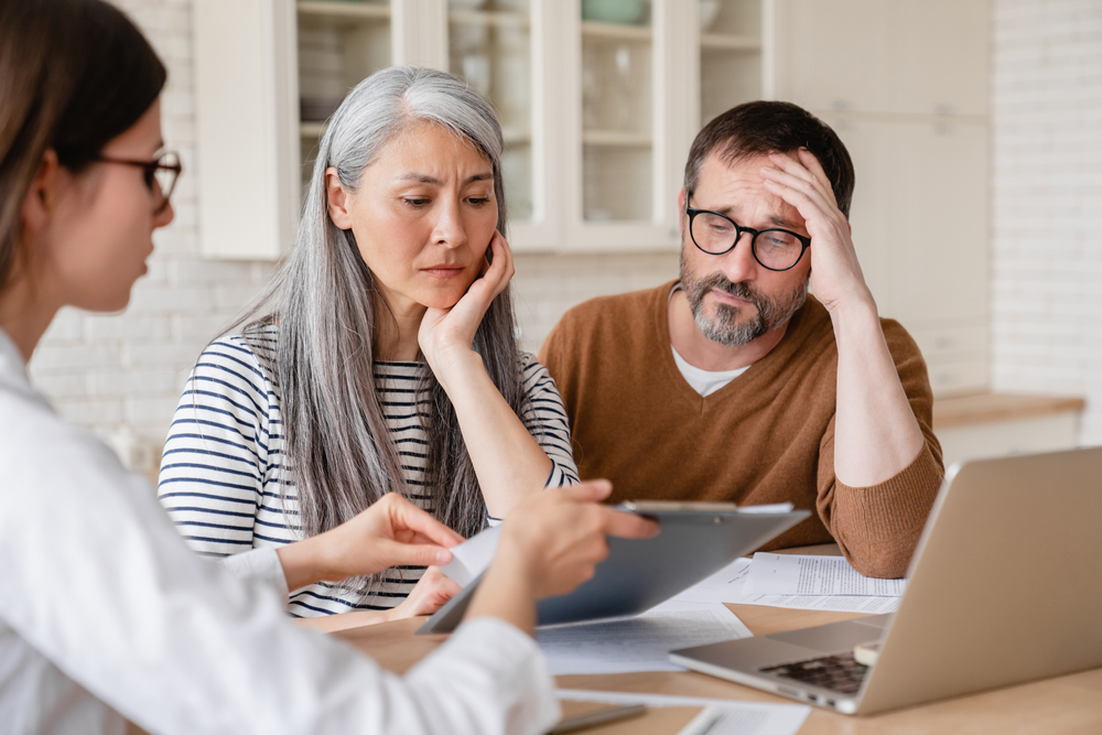 financial advisor lawyer consulting mature middle-aged couple showing them debts, bunkruptcy