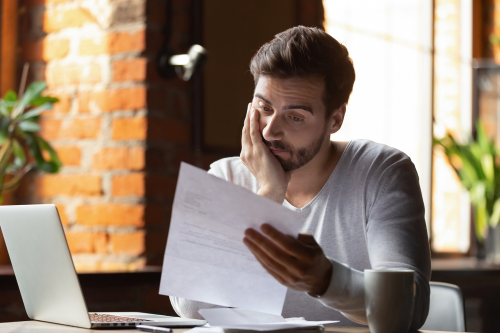confused frustrated young man reading letter in cafe, debt notification